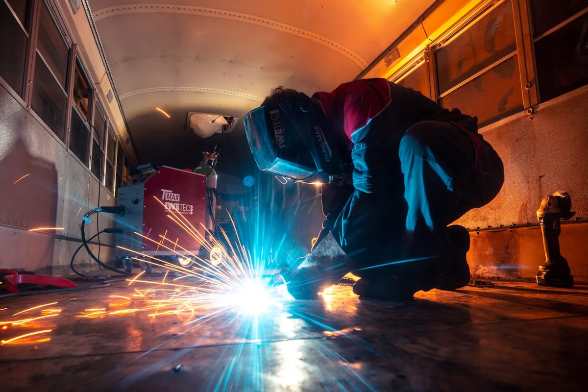 Industrial welder striking an arc beside a welding power source with sparks